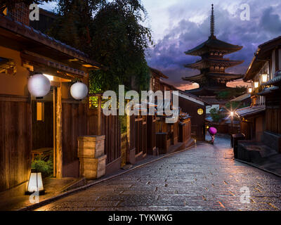 Donna in abito tradizionale sulla strada di Kyoto al tramonto - viola kimono & ombrello Foto Stock