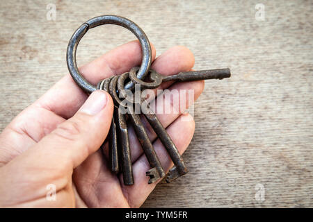 Mazzetto di diverse chiavi in mano su sfondo di legno Foto Stock