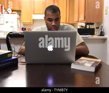 Tech. Sgt. Christopher McShan II, 341 Ingegnere Civile squadrone di gestione delle emergenze Flight capo sezione, lavora sul suo computer a casa sua a Malmstrom Air Force Base, Mont., nov. 17, 2016. McShan ha ricevuto recentemente il suo conferimento data per la sua festa di laurea nov. 15, e si prevede che il laureato potrebbero 2018. Foto Stock