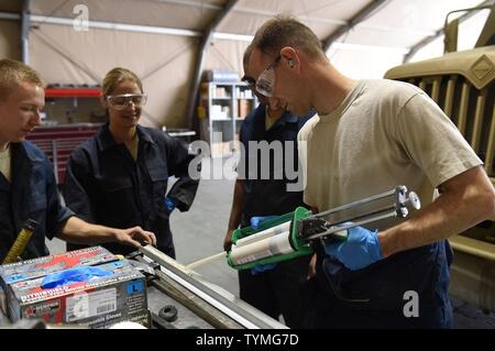 Il personale Sgt. Andrew, 380 Fire e Refueler veicolo Manutenzione manutentore, supporta un angolo trave mentre Col. Kevin Eastland, 380 Aria ala Expeditionary vice comandante, applica un industriale adesivo acrilico per il montaggio del fascio ad una R-11 camion di carburante in una località segreta nel sud-ovest Asia, 16 novembre 2016. Il fascio ad angolo è parte del kit di servizio per rafforzare i bordi di R-11 coppa del serbatoio, richiedendo la vernice da spellare al fine di creare un vero e proprio legame tra la trave e la vasca. Foto Stock