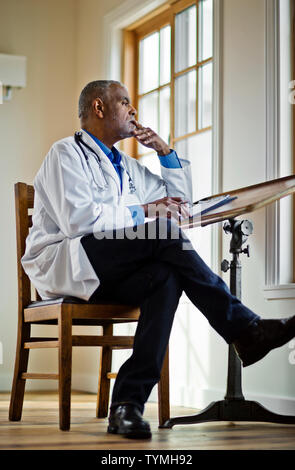 Medico seduto e pensare Foto Stock