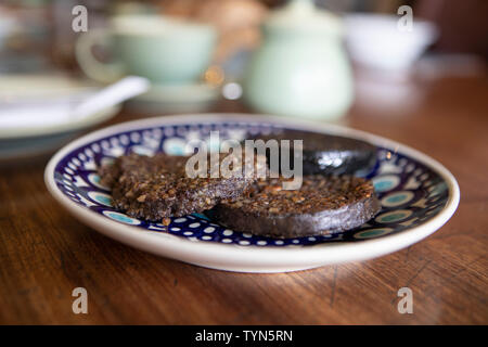 Haggis per colazione la colazione è servita su un dipinto a mano la piastra con uno sfondo sfocato Foto Stock