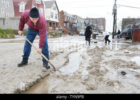 Raymond Manning badili un canale attraverso la sabbia al fine di deviare le acque di esondazione sinistra dall' uragano che sabbia sommersi il Rockaway Peninsular nel distretto di Queens su ottobre 30, 2012 in New York City. Il super tempesta che ha devastato parte della costa orientale ha chiesto ai funzionari di arrestare tutti i sistemi di trasporto pubblico e nelle scuole e per l'evacuazione di migliaia di persone che vivono nelle zone costiere. UPI /Monika Graff Foto Stock