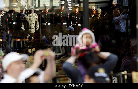 Le riflessioni di U.S. Marines in piedi di fronte alla strada si trovano dietro agli spettatori che guardare i veterani parata del giorno a New York City il 11 novembre 2012 in New York City. I veterani parata del giorno è stata organizzata a New York dal 1929. Oltre 25.000 persone partecipano alla parata di ogni anno. UPI/John Angelillo Foto Stock