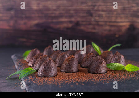 In casa tartufi di cioccolato con menta cosparso con polvere di cacao su ardesia. Focus sul tartufo Foto Stock