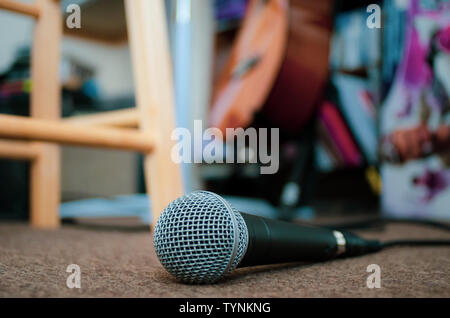 Microfono sul pavimento di moquette con copia spazio. Un microfono che giace sulla moquette del pavimento di un home studio musicale con copia spazio all'indietro. Foto Stock