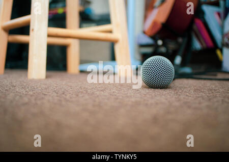 Microfono sul pavimento di moquette con copia spazio. Un microfono che giace sulla moquette del pavimento di un home studio musicale con copia spazio all'indietro. Foto Stock