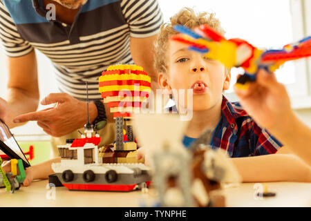 Naughty bambino. Bel ragazzo gioioso che mostra la sua lingua mentre si tenta di infastidire Foto Stock