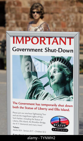 Una donna si ferma per leggere un cartello che spiega il motivo per cui la Statua della Libertà è chiuso a causa di un governo federale di arresto sul Ottobre 1, 2013 in New York City. Il governo federale di arresto che ha avuto inizio il martedì mattina inviato migliaia di non-essenziali basato a New York i dipendenti federali home e parzializzato Parco Nazionale di strutture, tra cui la Statua della Libertà. UPI/John Angelillo Foto Stock