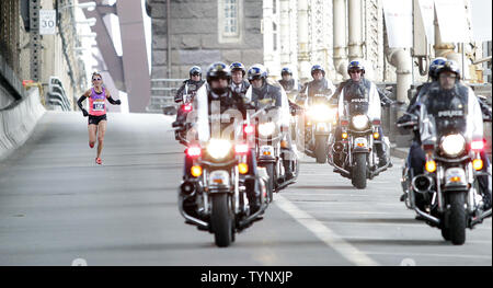 Una donna corre lungo il lato di polizia sulla moto durante la rampa in uscita dal 59th Street Bridge quando ella compete nella maratona di New York il 3 novembre 2013 in New York City. I 47.000 corridori gareggeranno attraverso cinque distretti per la prima volta dal Boston Marathon bombardamenti, che ha lasciato tre morti e più di 260 feriti in aprile. UPI /John Angelillo Foto Stock