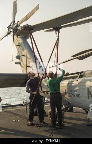 Golfo (nov. 19, 2016) Petty Officer di 2a classe di Gilbert Henson, sinistra e sottufficiali di seconda classe Brock Arnold diffondere le pale del rotore in preparazione per un prossimo rifornimento verticale a bordo del combattimento veloce nave appoggio USNS Arctic (T-AOE 8). Artico è implementato il supporto di coalizione forze marittime navi negli Stati Uniti Quinta Flotta area di operazioni. Foto Stock