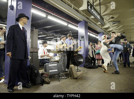 Un uomo vestito con i panni e la moda di inizio e a metà del XX secolo si erge e ascolta la musica dal vivo mentre un paio di balli in una metropolitana piattaforma come essi fanno tutti parte del treno Vintage evento presso il 2° Avenue stop sulla metropolitana di New York City il 14 dicembre 2014. Treno Vintage è un tutto il giorno musica underground e dance party che è volontario. UPI/John Angelillo Foto Stock