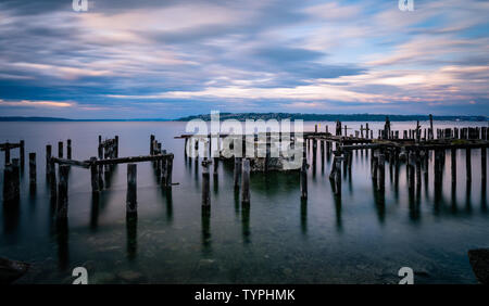 Una lunga esposizione tramonto d'acqua,nuvole,e palificazioni, Tacoma Washington Foto Stock