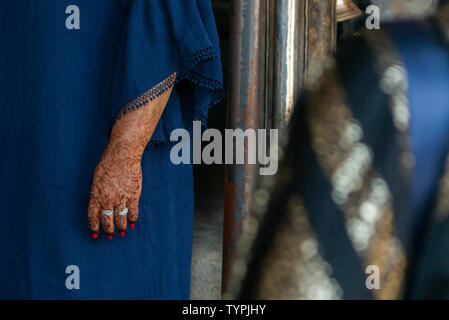 Close up di un tradizionalmente verniciati con braccio di henna indossare anelli d'argento e blu tradizionale abbigliamento con un primo piano sfocato Foto Stock