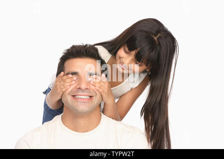 Ragazza indiana che copre il padre gli occhi da dietro e sorridente Foto Stock