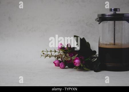 Sfondo marmo e fiori di colore rosa con tazza da caffè e ciambelle di merletto e blocco note Foto Stock