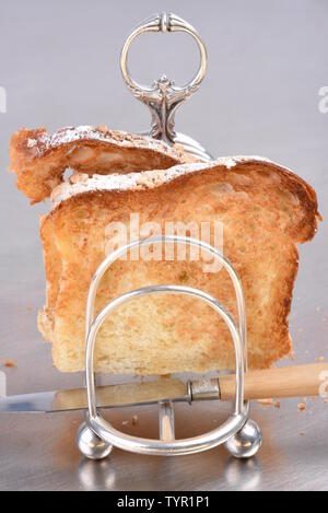 La colazione era fresca, toast in rack e il coltello sul grigio metallico tabella, primo piano Foto Stock