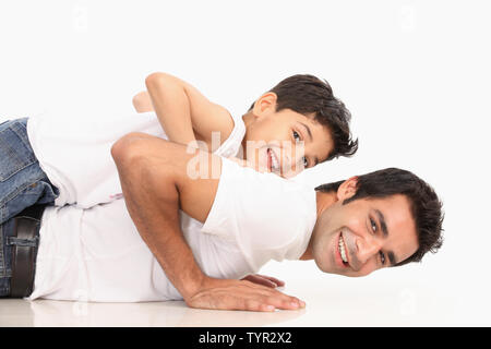 Padre facendo push-up con figlio sulla sua schiena Foto Stock