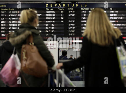 Due le donne guardano a bordo del treno Partenze come pendolari e viaggiatori in vacanza fanno la loro strada attraverso la Penn Station su dicembre 22, 2015 in New York City. Un record di 100 milioni di americani sono attesi a viaggiare per i quattro giorni di periodo natalizio. Foto di Giovanni Angelillo/UPI Foto Stock