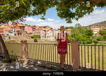 Donna in piedi sotto gli alberi guardando il grazioso villaggio spagnolo di Bezas nel Siera de Albarracin Spagna Foto Stock