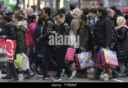 Pedoni attraversare la strada tenendo borse per lo shopping vicino al grande magazzino Macy's in Herald Square sul Venerdì nero a New York City il 25 novembre 2016. Per oltre un decennio, Venerdì nero è stata tradizionalmente la partenza ufficiale per l'acquisto di occupato binge racchiuso a sandwich tra il rendimento di grazie e di Natale. Foto di Giovanni Angelillo/UPI Foto Stock