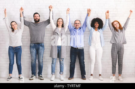 Gruppo di successo della gente amichevole alzando le mani collegato Foto Stock