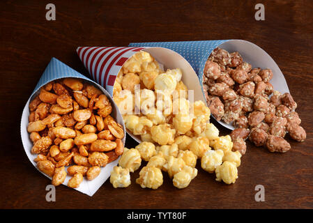 Il miele arachidi con caramello e popcorn closeup di miele semi di sesamo mandorle in coni di carta Foto Stock