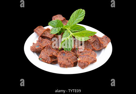 Close up tradizionale turca antipasto polpette di greggio - cig kofte con la menta in isolati su sfondo nero, il fuoco selettivo. Foto Stock