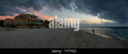 Bella vista panoramica del villaggio vacanza sulla spiaggia di sabbia durante una drammatica NUVOLOSO TRAMONTO. Prese a Varadero, Cuba. Foto Stock