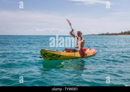 Il sambuco montare l uomo è il kayak su un giallo brillante kayak in mare dei Caraibi durante una soleggiata giornata estiva. Prese a Varadero, Cuba. Foto Stock