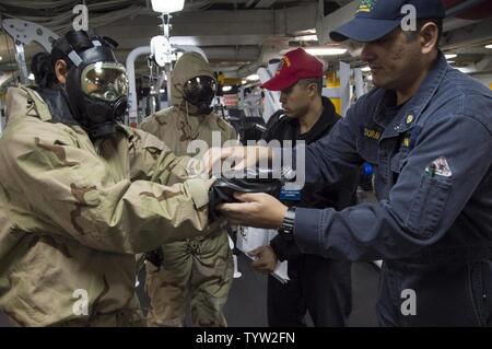 SASEBO, Giappone (nov. 30, 2016) Chief Petty Officer Rodney Duran (a destra), assegnato a galla gruppo Formazione Pacifico Occidentale, assiste Petty Officer di terza classe Laniece Watters, da Columbus, Ohio, con indossare le sostanze chimiche e biologiche dei guanti di protezione durante un chimico, biologico, radiologico praticare a bordo di assalto anfibio nave USS Bonhomme Richard (LHD 6). Bonhomme Richard, distribuita a Sasebo, Giappone, serve in avanti per fornire una rapida capacità di risposta in caso di emergenza regionale o calamità naturali. Foto Stock