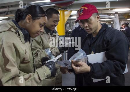 SASEBO, Giappone (nov. 30, 2016) Senior Chief Petty Officer Herbert Calilung (a destra), da Yigo, Guam, offre corsi di formazione per sottufficiali di terza classe Laniece Watters, da Columbus, Ohio, sulla chimica/biologica equipaggiamento protettivo durante un chimico, biologico, radiologico praticare a bordo di assalto anfibio nave USS Bonhomme Richard (LHD 6). Bonhomme Richard, distribuita a Sasebo, Giappone, serve in avanti per fornire una rapida capacità di risposta in caso di emergenza regionale o calamità naturali. Foto Stock