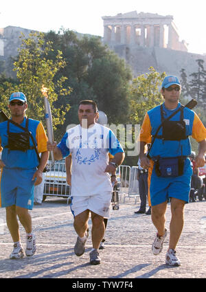 La fiamma olimpica portati dagli ex greca Olympic weightlifter Charalampos Cholidis lascia l'acropoli nelle prime ore del mattino, 13 agosto 2004, sulla sua strada verso lo stadio olimpico per la cerimonia di apertura di Atene del 2004 Olimpiadi estive più tardi nella giornata. (UPI foto / Heinz Ruckemann) Foto Stock