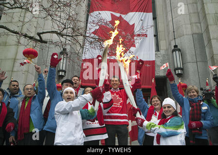 Portatore di torcia Brian Bogdanovich (L), un vigile del fuoco, passa la fiamma olimpica a Constable Tanya McLachlan davanti ad un tifo Vancouver Sindaco Gregor Robertson sul giorno 105 della Vancouver 2010 Inverno Torcia Olimpica sui passi del nord della città di Hall in Vancouver, British Columbia, 11 febbraio 2010. UPI /Heinz Ruckemann Foto Stock