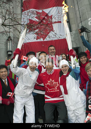 Portatore di torcia Brian Bogdanovich (L), un vigile del fuoco, passa la fiamma olimpica a Constable Tanya McLachlan con un tifo Vancouver Sindaco Gregor Robertson in mezzo al giorno 105 della Vancouver 2010 Inverno Torcia Olimpica sui passi del nord della città di Hall in Vancouver, British Columbia, 11 febbraio 2010. UPI /Heinz Ruckemann Foto Stock