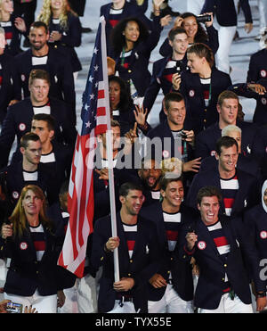 Michael Phelps tiene la bandiera americana come egli conduce gli Stati Uniti nell'arena in occasione della cerimonia di apertura del Rio 2016 Olimpiadi di estate inizia a Rio de Janeiro in Brasile il 5 agosto 2016. Foto di Terry Schmitt/UPI Foto Stock