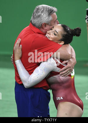 Ginnasta americano Aly Raisman (R) è abbracciato da coach Mihai Brestyan dopo che aveva completato la sua routine nell'esercitazione del pavimento durante la donna ginnastica artistica Team finali del Rio 2016 Olimpiadi di estate a Rio de Janeiro, Brasile, 9 agosto 2016. Il team americano ha vinto la medaglia d'Oro, la bordatura fuori i russi che hanno vinto la medaglia d'argento e il Cinese ha vinto il bronzo. Foto di Mike Theiler/UPI Foto Stock