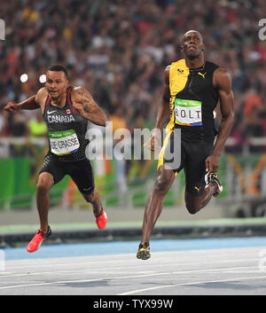 Medaglia d'oro della Giamaica Usain Bolt porta medaglia di bronzo Andre De Grasse (possibile) sulla linea del traguardo per vincere gli Uomini 100m Finale con un tempo di 9,81 allo Stadio Olimpico presso il Rio 2016 Olimpiadi di estate a Rio de Janeiro, Brasile, il 14 agosto 2016. Foto di Terry Schmitt/UPI Foto Stock