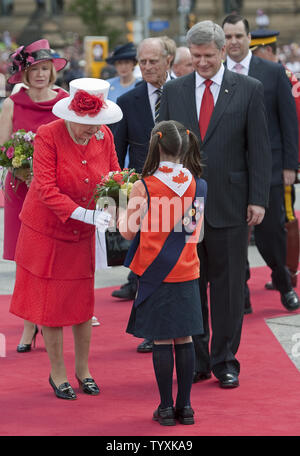 Magno Harper (retro) accompagna il principe Filippo (Medio) mentre in Canada il Primo Ministro Stephen Harper guarda su come la Gran Bretagna la regina Elisabetta riceve fiori da un giovane membro dell'Brownies durante il Canada alle celebrazioni del Giorno sulla Collina del Parlamento a Ottawa, Ontario, Luglio 1, 2010. La coppia reale sono il giorno quattro di loro nove giorno Royal Tour del Canada. UPI/Heinz Ruckemann Foto Stock