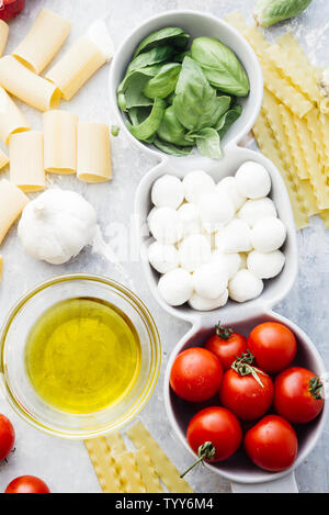 Pomodoro e Basilico mozzarella. Ingredienti alimentari pattern con mozzarella di sfere e di foglie di basilico fresco, round di pomodori ciliegini, con pasta e vino Foto Stock