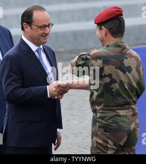 Il Presidente francese Francois Hollande scuote le mani con un soldato di Place de la Concorde durante l annuale per il giorno della Bastiglia parata militare a Parigi il 14 luglio 2015. Foto di David Silpa/UPI Foto Stock