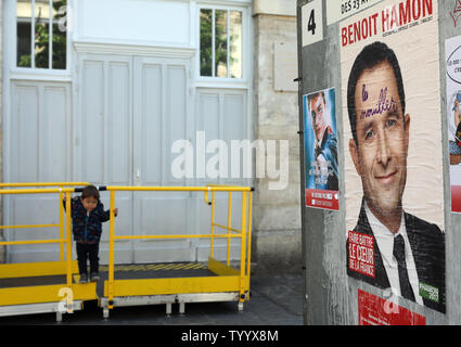 Un bambino gioca accanto a una campagna di manifesti del rightwing socialista elezioni presidenziali contender Benoit Hamon sul loro modo di esprimere il loro voto per il primo turno di votazione a Parigi il 23 aprile, 2017. Il voto è in corso nel primo round di un imprevedibile elezioni presidenziali il cui esito potrebbe rivelarsi cruciale per il futuro di un profondamente diviso il paese e un nervoso Unione europea. Foto di Maya Vidon-White/UPI Foto Stock