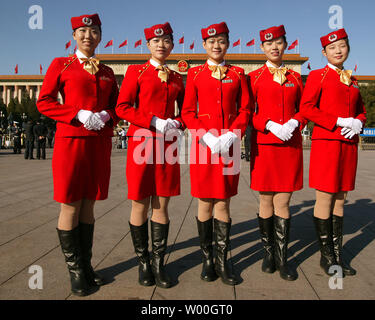 Delegato cinese hostess posano per una foto onTiananmen piazza durante la cerimonia di apertura del XVII congresso di partito presso la Grande Sala del Popolo (fondo) a Pechino il 15 ottobre 2007. L'elite della Cina del Partito comunista ha aperto loro quinquennale congresso, un evento ampiamente previsto per vedere il presidente Hu Jintao ha approvato come la nazione leader per altri cinque anni. (UPI foto/Stephen rasoio) Foto Stock