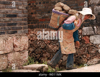 Scarsa minoranza etnica cinese di caricare a mano in mattoni di fango su di un carrello da una vecchia casa per essere demolita per far posto ad un nuovo hotel di Lijiang, nord della provincia dello Yunnan, il 30 settembre 2012. Le disparità di reddito continua a crescere in Cina come rurale la povertà persiste nonostante la rapida crescita urbana. La Cina ha sollevato la soglia di povertà di $ 1 al giorno a persona in 2011, aumentando del paese colpito dalla povertà della popolazione da 26.99 milioni a 128 milioni. UPI/Stephen rasoio Foto Stock