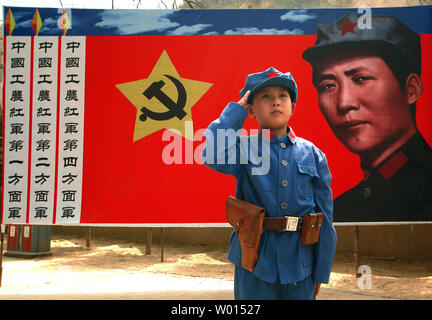 Un ragazzo cinese vestito in uniforme comunista in posa per una foto di fronte a un banner del partito comunista soldato ideale Li Feng, in corrispondenza di un sito utilizzato da ex timoniere Mao Zedong e altri leader per discutere di politica e strategie future in Yangjialing Rivoluzione, Yan'an, Provincia di Shaanxi, il 6 aprile 2014. Yan'an era vicino alla terminazione della lunga marcia, e divenne il centro del sistema cinese di rivoluzione comunista ha portato il mio Mao dal 1936 al 1948. Comunisti cinesi celebrano la città come il luogo di nascita della Cina moderna e il culto di Mao. UPI/Stephen rasoio Foto Stock