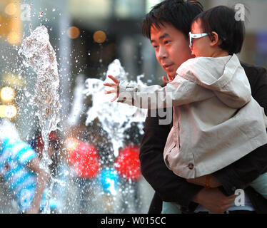 Un Cinese padre e figlio godono di una fontana di acqua in corrispondenza di un centro commerciale a Pechino il 27 maggio 2014. La Cina si sta preparando per 2 milioni di neonati extra un anno come risultato di un allentamento dei suoi " un bambino' politica che consentirà a più coppie di avere due bambini. UPI/Stephen rasoio Foto Stock