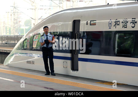 Un cinese la guardia di sicurezza sta accanto a uno della Cina il più recente e veloce 'bullet treni' in corrispondenza di un hi-speed rail hub a Pechino il 15 settembre 2017. La Cina ha gettato più di 12.400 miglia di hi-speed rail con un bersaglio di aggiungere un altro 6,214 miglia dal 2020, rendendo la rete più grande al mondo. Foto di Stefano rasoio/UPI Foto Stock