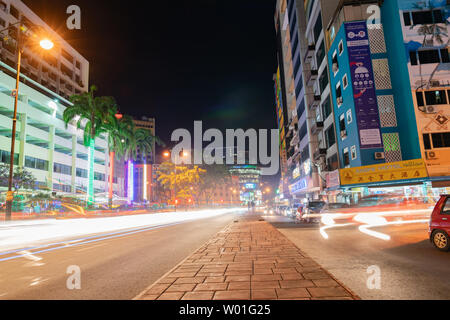 KOTA KINABALU BORNEO - 30 maggio 2019; Street scene con luci al neon e sentieri di luce dalle vetture in movimento in una lunga esposizione Foto Stock