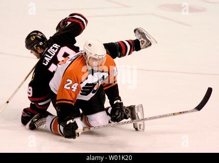 I volantini' Sami Kapanen (24) striscia fuori da sotto il Blackhawks' Kyle Calder (19) come host di Philadelphia Chicago in un gioco serale presso il Wachovia Center di Philadelphia, il 24 febbraio 2004. (JON ADAMS/UPI) Foto Stock
