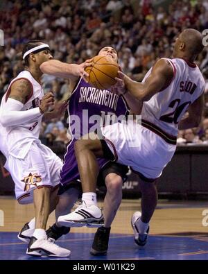 Il re' Mike Bibby (10) cade avente diventare intrappolati con il 76ers' Eric Nève (20) e Allen Iverson (3) come host di Philadelphia Sacramento in un gioco serale presso il Wachovia Center di Philadelphia, il 4 marzo 2004. (UPI PHOTO/ JON ADAMS) Foto Stock